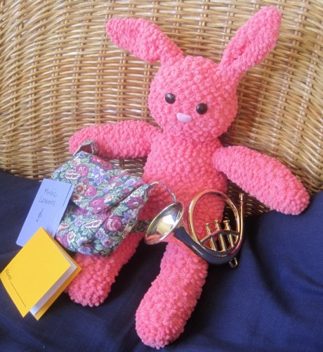This bunny has a flowery backpack with a French horn, sheet music and a yellow notebook.
